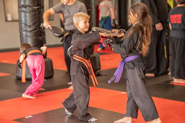 A young boy and girl are practicing martial arts.